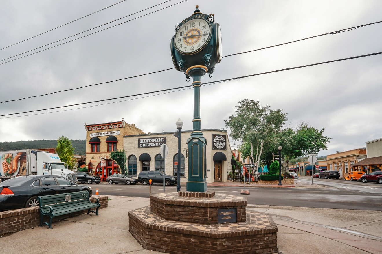 Street view in a historic town with a distinctive turquoise clock, old buildings, and cars parked along the curb